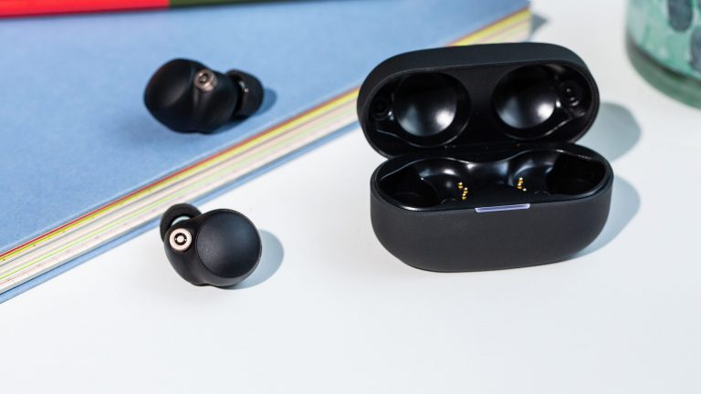 Sony WF 1000XM4 Das aufgeklappte Ladecase der Sony WF 1000XM4 In-Ear-Kopfhörer liegt auf einem Tisch. Daneben liegen die beiden kabellosen Kopfhörer.