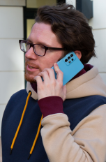 Eine Person hält sich ein Samsung Galaxy A52S ans Ohr, um zu telefonieren.