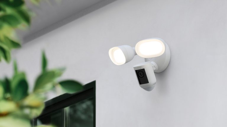 Ring Floodlight Cam Wired Pro Eine Ring Cam Floodlight hängt an der Außenfassade eines Hauses.