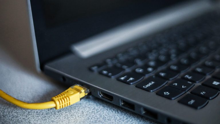 WLAN geht nicht Detailansicht eines LAN-Kabels, das im entsprechenden Port an einem Laptop steckt.