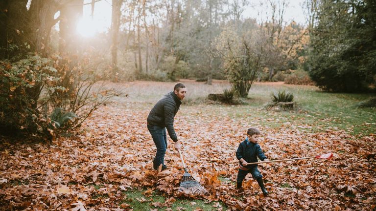 Funkklingeln Vater und Sohn haken im Garten Laub zusammen.