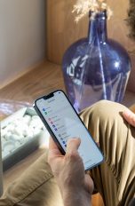 Eine Person liegt auf dem Sofa und bedient gerade ein iPhone.