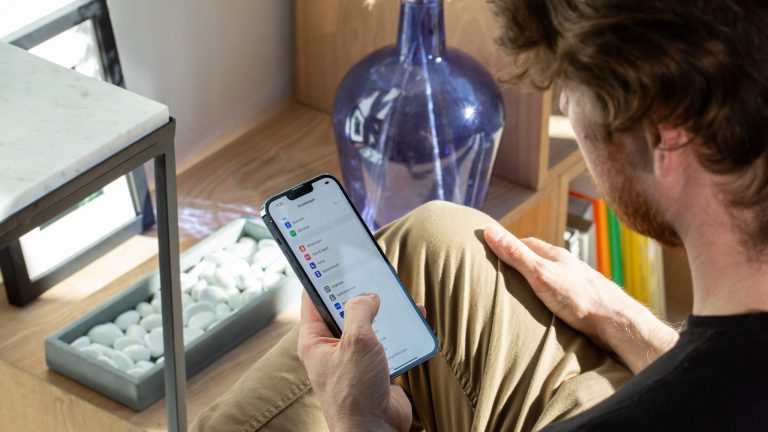 Eine Person liegt auf dem Sofa und bedient gerade ein iPhone.