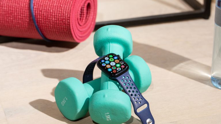 Apple Watch 7 Eine Apple Watch 7 liegt auf zwei Hanteln, daneben liegt eine Sportmatte.