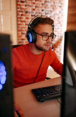 Eine Person mit einem Headset auf dem Kopf sitzt vor einem Gaming-PC.