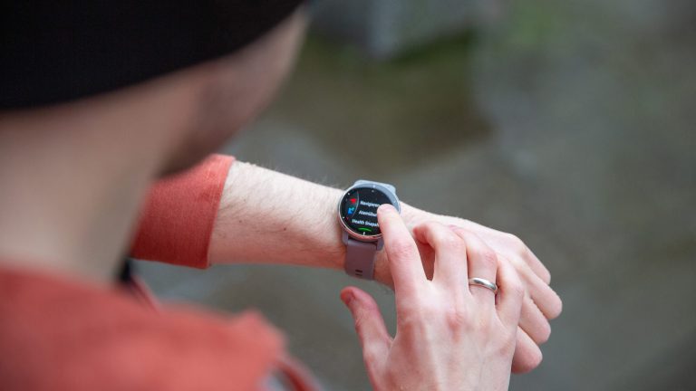 Laufen im Frühjahr Eine Person mit einem Fitnesstracker am Handgelenk bedient dessen Touchdisplay.