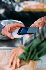Eine Person zahlt mit einem Smartphone an einem Marktstand.