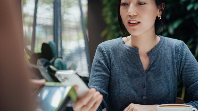 Mobiles Bezahlen Eine Person hält ein Smartphone an ein Kartenterminal.