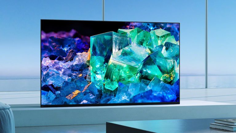 Ein Sony BRAVIA XR A95K steht auf einer TV-Bank vor einem großen Fenster.