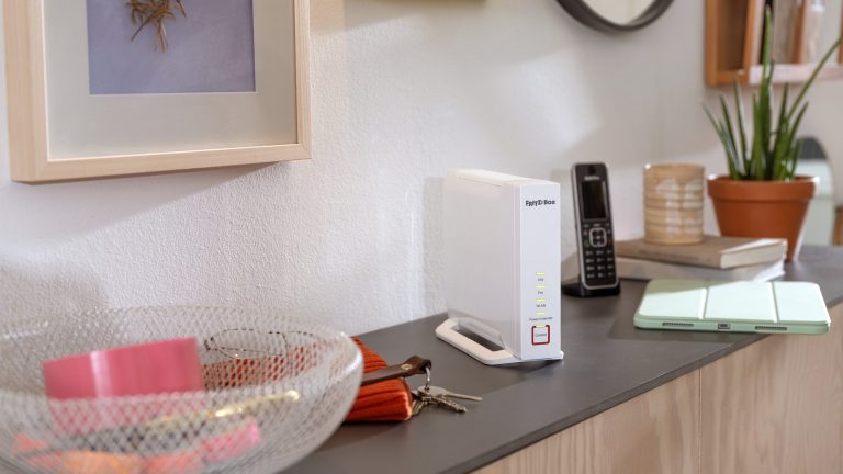Fritzbox 4060 Eine Fritzbox 4060 steht auf einem Sideboard neben einer Pflanze, einem Telefon und einem Schlüsselbund.