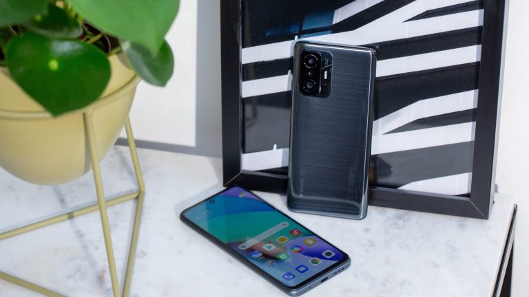 Xiaomi Redmi 10 und Mi 10T Auf einem Tisch befinden sich zwei Geräte des Xiaomi Mi 10T, eines liegt, eines steht an der Wand.