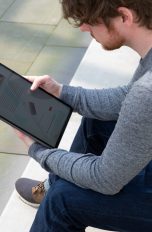Eine Person sitzt auf einer Treppe und schaut auf ein iPad Pro.