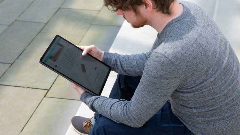 Eine Person sitzt auf einer Treppe und schaut auf ein iPad Pro.