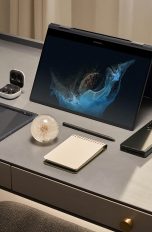 Ein Samsung Galaxy Book2 Pro 360 steht aufgeklappt auf einem Schreibtisch. Daneben liegen weitere Samsung- und Büro-Artikel.