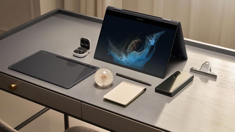 Ein Samsung Galaxy Book2 Pro 360 steht aufgeklappt auf einem Schreibtisch. Daneben liegen weitere Samsung- und Büro-Artikel.