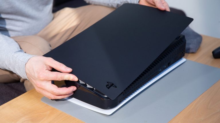 PlayStation 5: So wechselst du die Seitenteile Eine Person schiebt ein schwarzes Seitenteil auf eine liegende PlayStation 5.