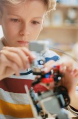 Ein Schulkind sitzt konzentriert vor einem Lernroboter.