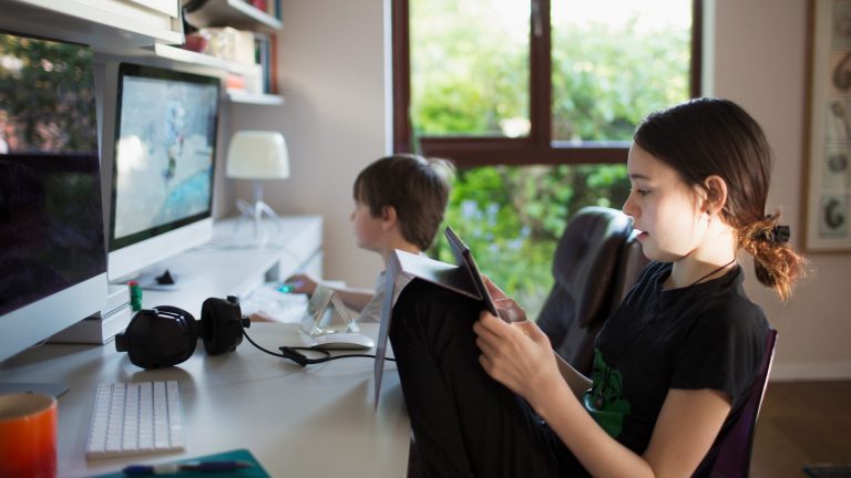 schnelle Router für Gamer Zwei Kinder sitzen am Schreibtisch vor zwei Computern, eines der Kinder hält ein Tablet in den Händen.