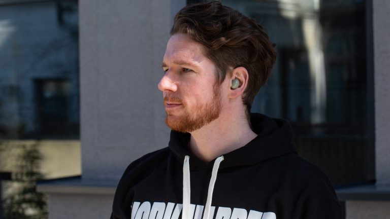 Samsung Galaxy Buds Eine Person steht vor einer Hauswand. In den Ohren trägt sie die Samsung Galaxy Buds2.