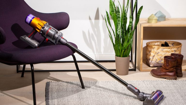 Dyson V12 Ein Dyson V12 Slim absolute lehnt an einem Sessel.