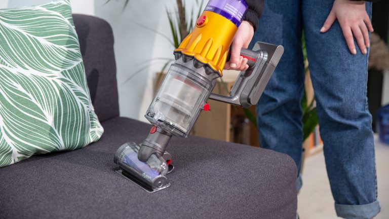 Dyson V12 Eine Person saugt mit dem Dyson V12 Slim absolute im Handsaugerformat einen Sessel.