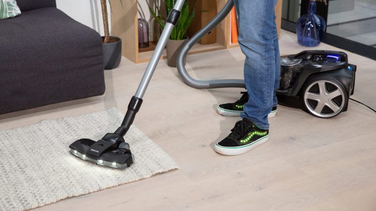 Philips Bodenstaubsauger FC9741-09/03 Eine Person saugt einen Läufer.
