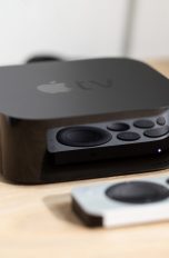 Ein Apple TV samt Remote liegt auf einem Tisch.