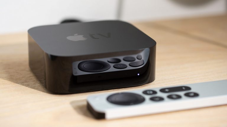 Ein Apple TV samt Remote liegt auf einem Tisch.