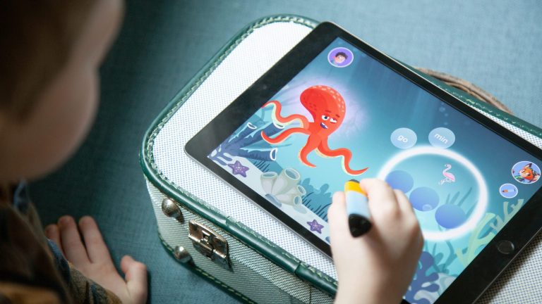Ein Kind sitzt vor einem Tablet und zeichnet darauf mit einem digitalen Stift.