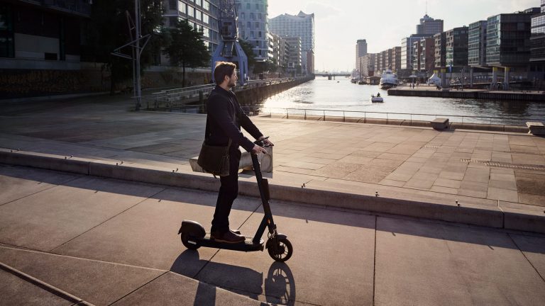 Eine Person fährt mit einem E-Scooter durch die Hamburger Hafen City.