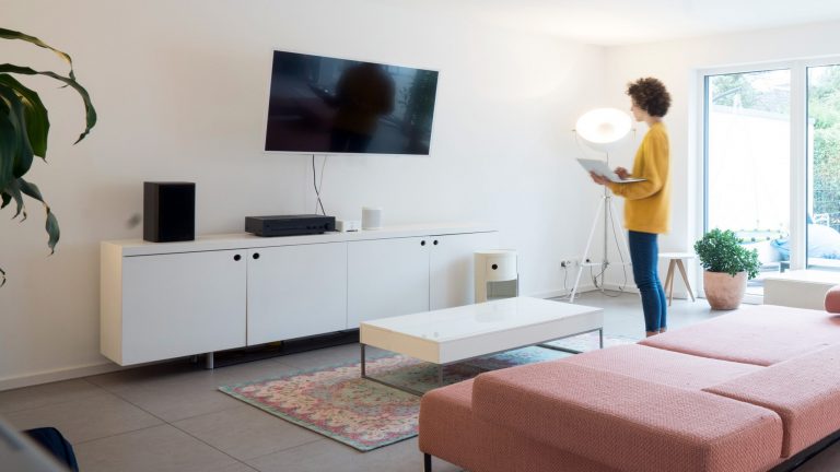 Eine Person steht mit einem Laptop vor einem Fernseher.