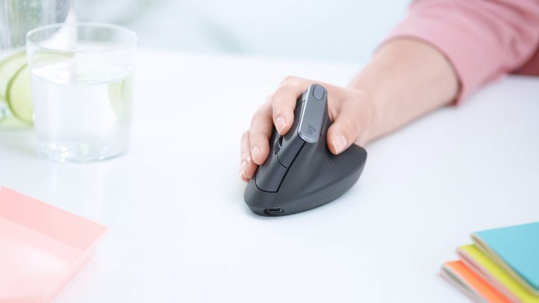 Logitech MX Vertical Eine Hand führt eine ergonomische Maus über einen Tisch.