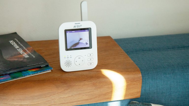 Philips Avent Video-Babyphone Das Elternteil des Babyphons Avent SCD 833/26 von Philips steht auf einer Sofalehne. Auf dem Display ist der Blick in ein Kinderzimmer zu erkennen.