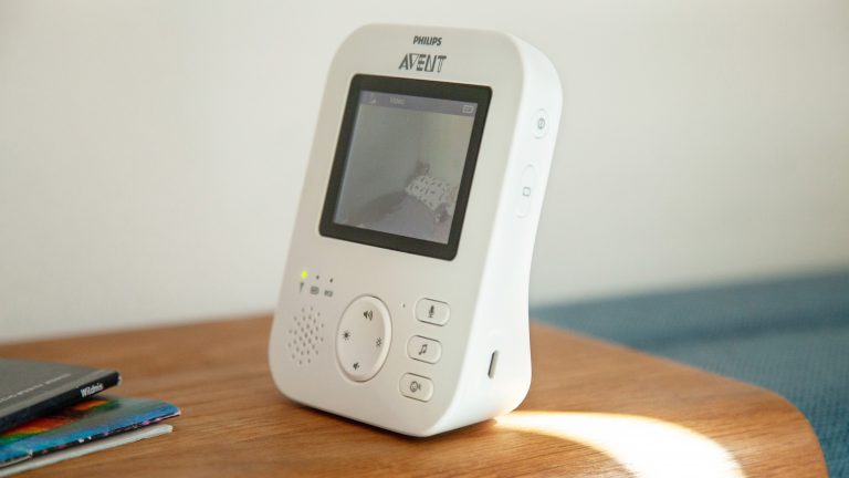 Philips Avent Video-Babyphone Das Elternteil des Babyphons Avent SCD 833/26 von Philips steht auf einer Sofalehne. Auf dem Display ist der Blick in ein Kinderzimmer zu erkennen.