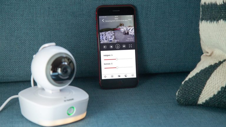 Reer Video-Babyphone IP BabyCam Smart Eine Reer IP Babycam Move steht neben einem Smartphone auf einem Sofa. Auf dem Display sind diverse Einstellungsoptionen der Kamera zu erkennen.