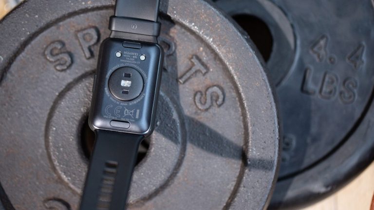 Huawei Watch Fit Eine Huawei Watch Fit liegt rückseitig auf einigen Hantelscheiben. Zu erkennen sind die Sensoren des Fitness-Trackers.