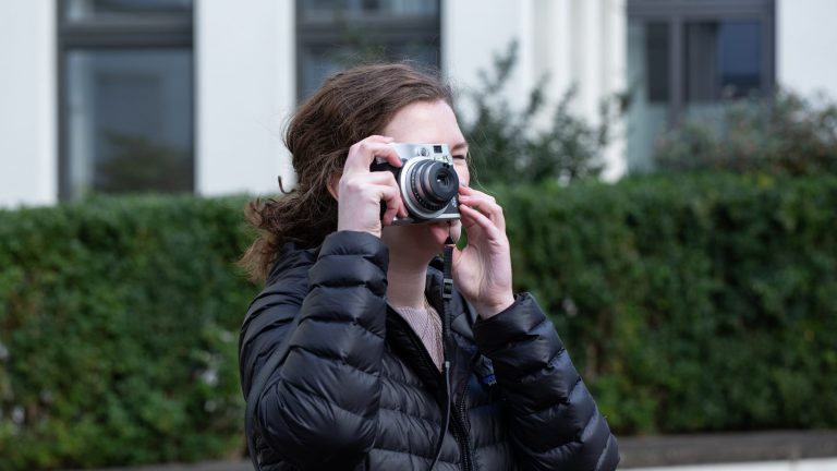 Fujifilm Instax mini 90 Neo Classic Eine Person schaut durch den Sucher einer Instax mini 90 Neo Classic.