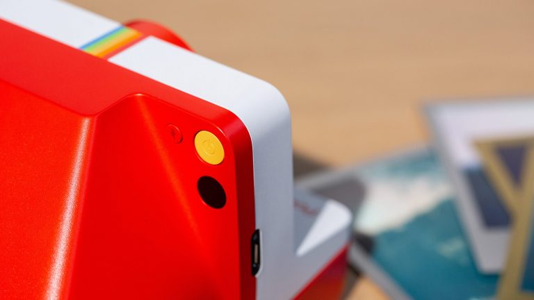 Polaroid Now Detailaufnahme der Rückseite einer Polaroid-Kamera. Zu erkennen sind unter anderem die Taste für den Auslöser und den Blitz.