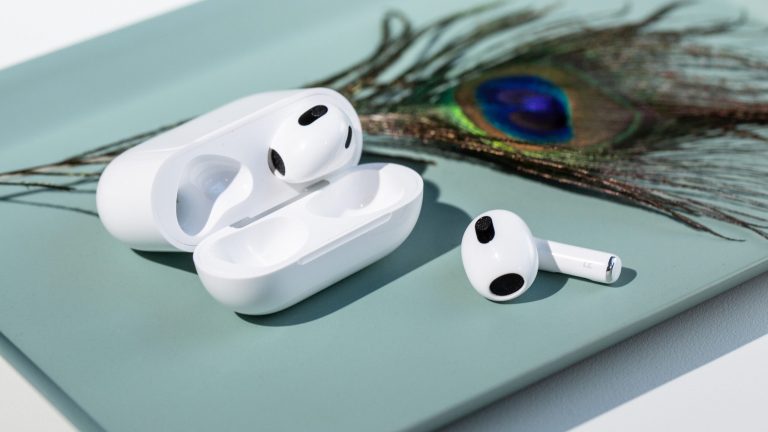 Zwei In-Ear-Kopfhörer liegen auf einem Tablet daneben ein Pfauenauge.
