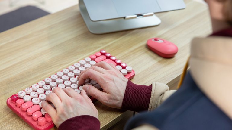 Logitech Pop Keys Eine Person tippt auf einer rosafarbenen Logitech Pop Keys.
