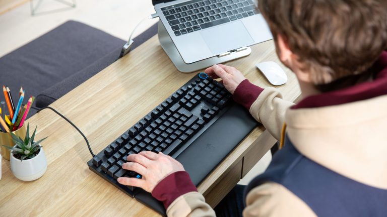 Eine Person sitzt an einem Schreibtisch vor einer Razer Huntsman V2.