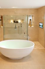 Ein Badezimmer mit freistehender Badewanne und einem Fernseher in der Wand.