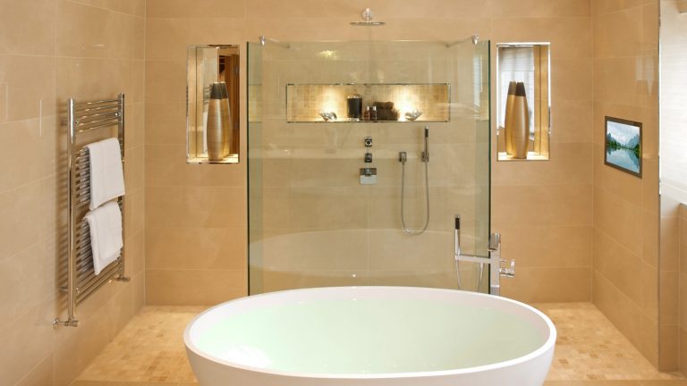 Ein Badezimmer mit freistehender Badewanne und einem Fernseher in der Wand.