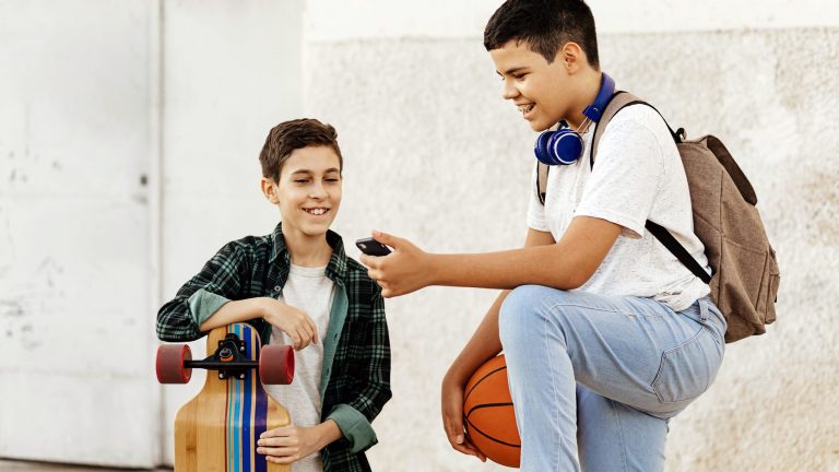 iOS 16 Lieblingsfeatures Zwei junge Menschen mit Longboard und Basketball schauen gemeinsam auf ein Smartphone.