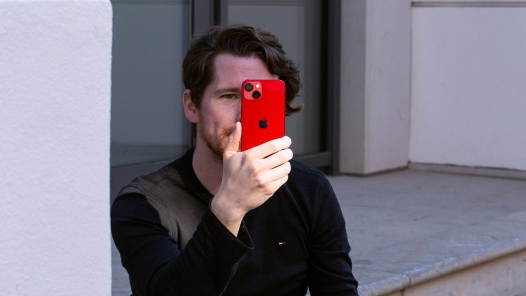 iPhone 13 Eine Person hält das iPhone 13 vor ihrem Gesicht.