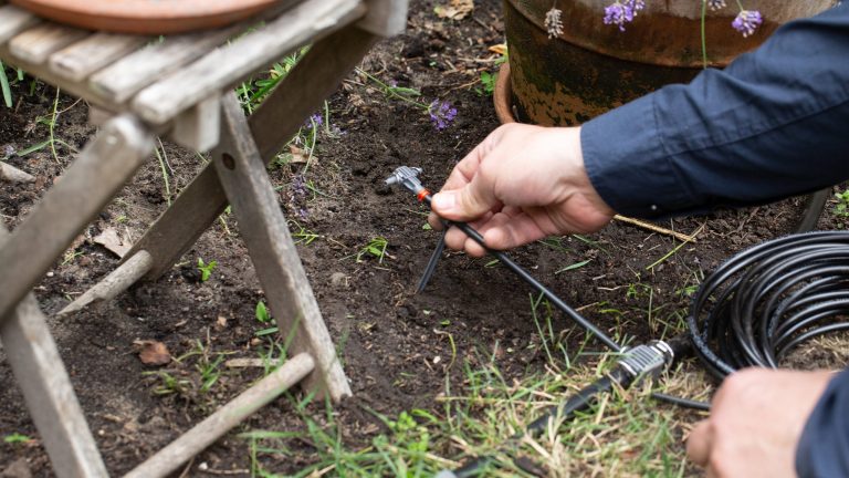 Gardena smart Water Control Eine Person befestigt einen Bewässerungsschlauch in der Erde.