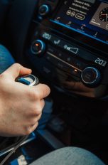 Eine Person betätigt die Gangschaltung in ihrem Auto.