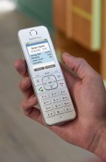 Eine Person hält ein Fritz!Fon C6 von AVM in Weiß in der Hand und schaut auf das Display.