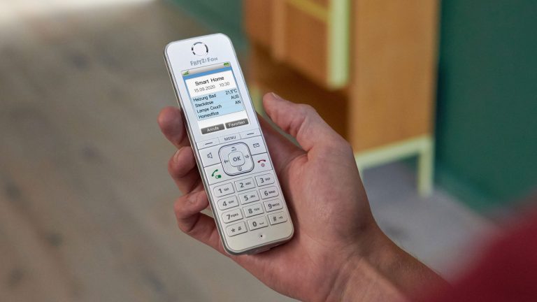 Eine Person hält ein Fritz!Fon C6 von AVM in Weiß in der Hand und schaut auf das Display.