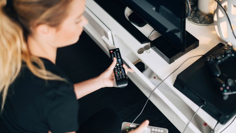 Fernseher zeigt kein Bild Eine Person mit Fernbedienungen in der Hand hockt vor einem Fernseher und einer Spielekonsole.